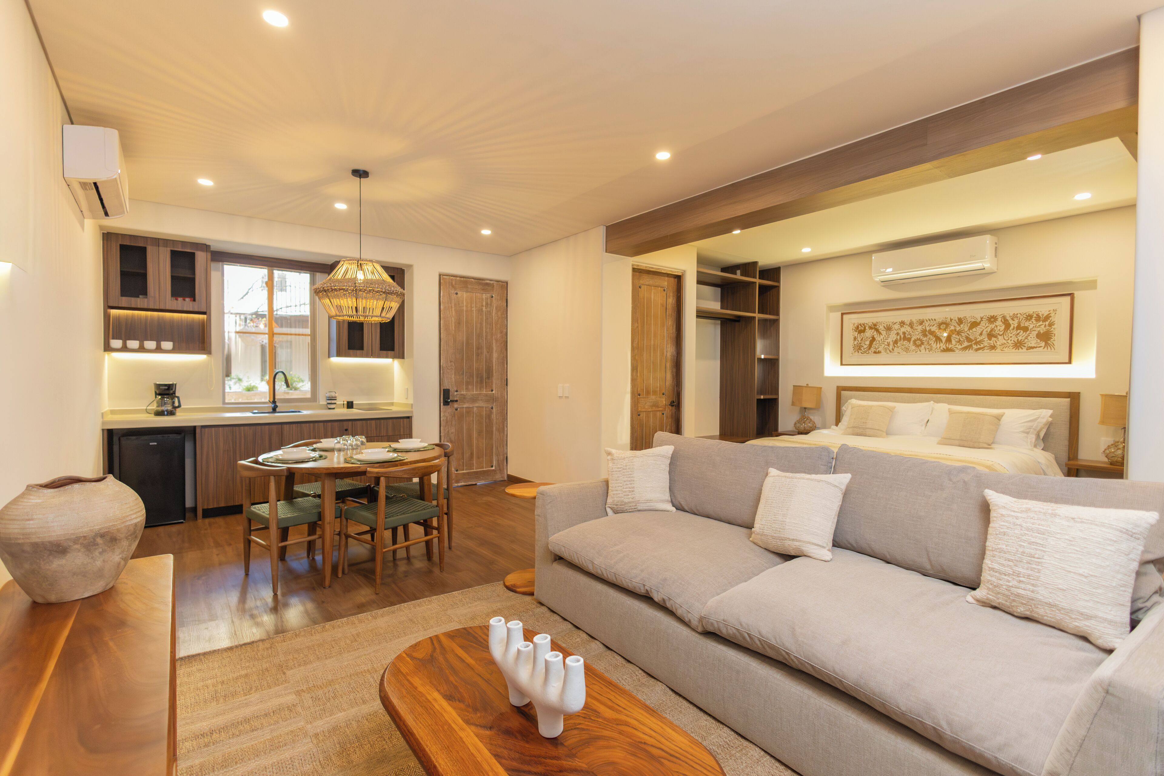 A modern living room with a sofa, a dining table, and a kitchen area.