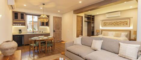 A modern living room with a sofa, a dining table, and a kitchen area.