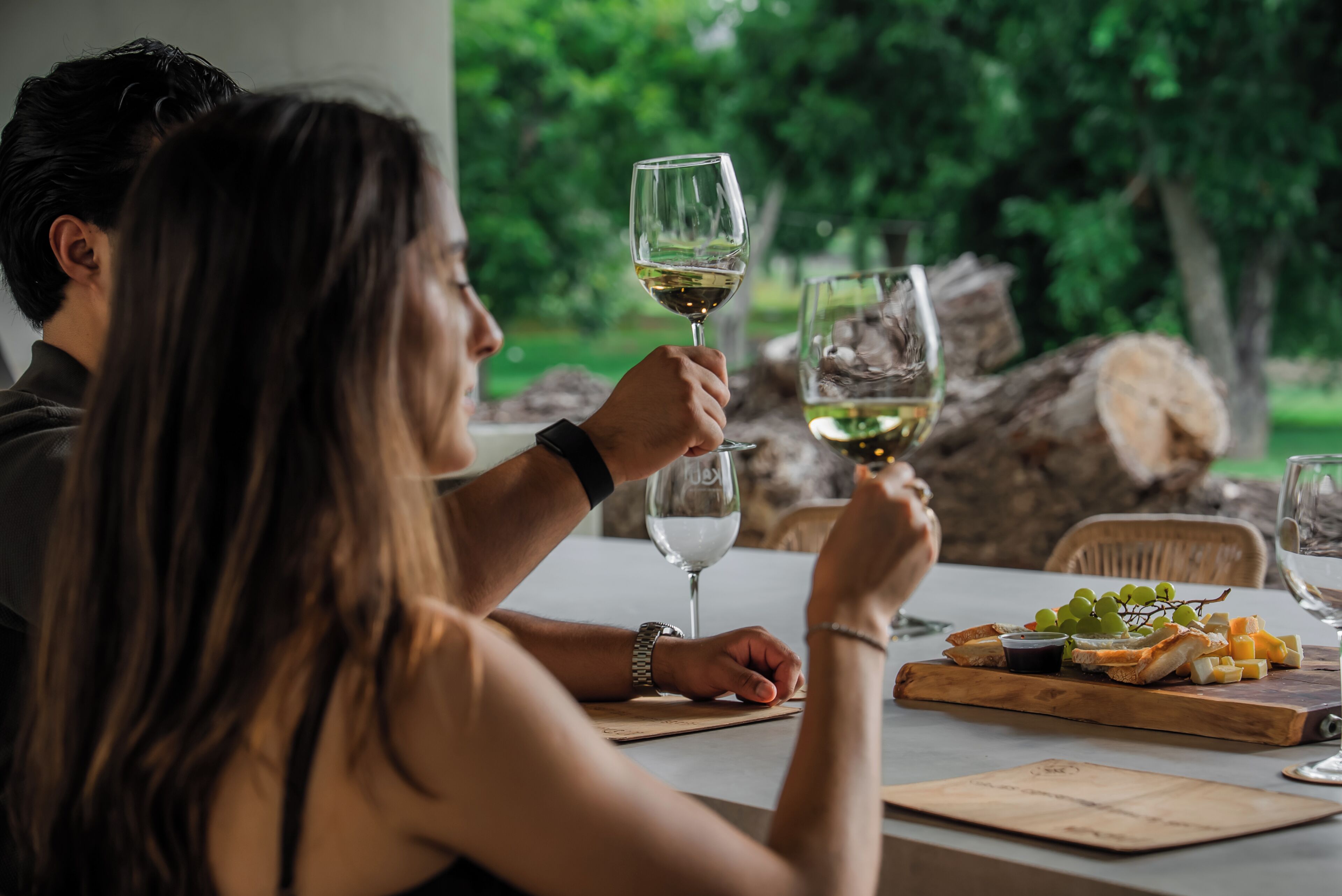 A dining table with a wooden board, glasses, and a bottle.