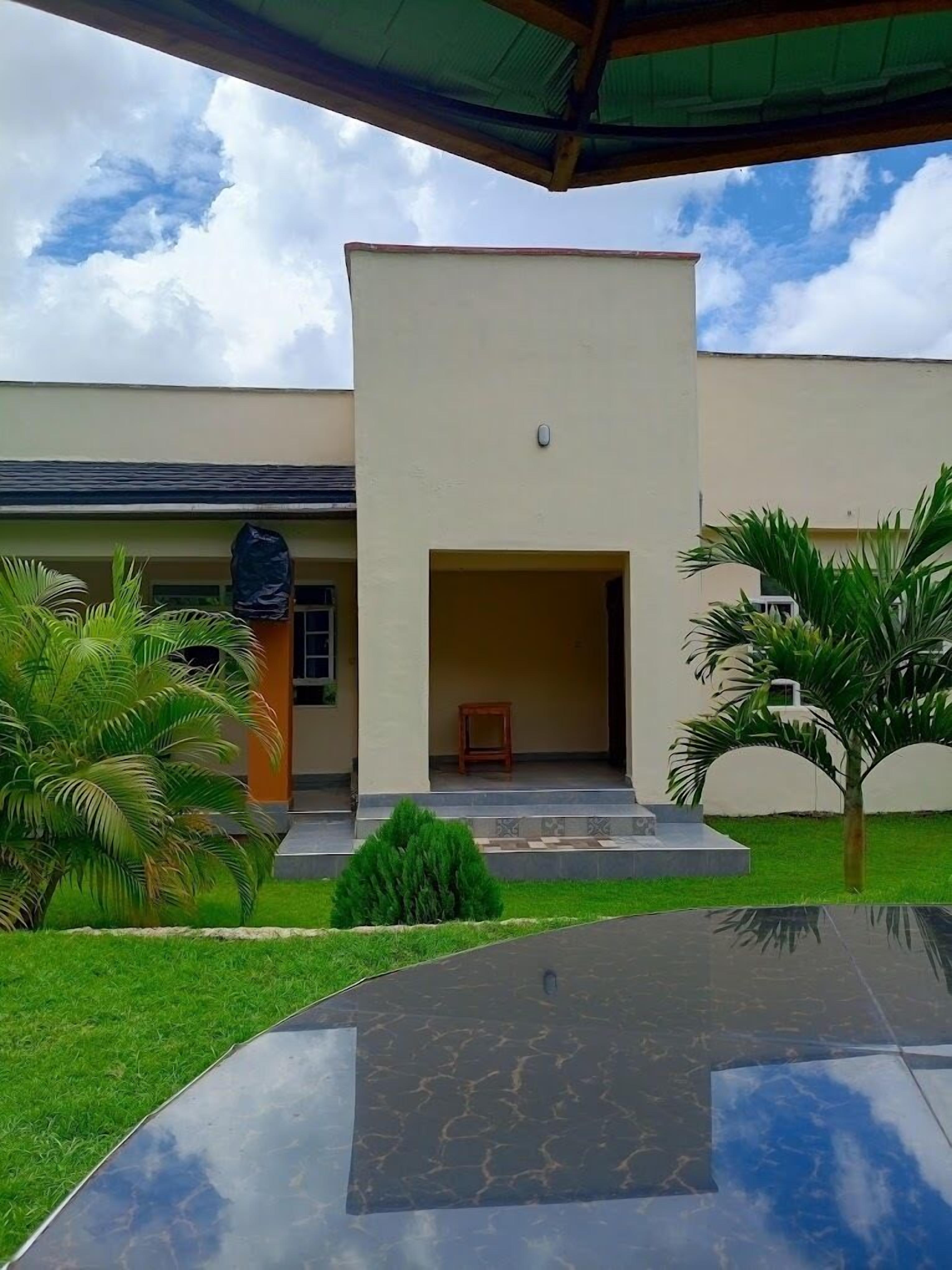 A modern building with a flat roof, a large entrance, and a small wooden table outside.