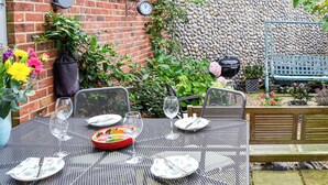 Eine Terrasse mit Tisch für zwei Personen, umgeben von einer Ziegelmauer und einer Steinmauer.