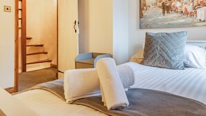 Ein Hotelzimmer mit Bett, einem Bild an der Wand, einer Tür und einer Treppe.