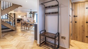 Ein modernes Interieur mit Fischgrätparkett, einer Treppe, einem Essbereich und einer Holztür.