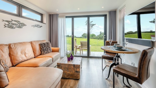 Ein modernes Wohnzimmer mit einer Ledersofa, einem Holztisch und einem Essbereich mit Tisch und Stühlen.