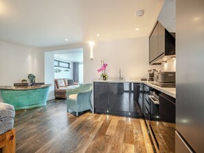 A modern kitchen with a black countertop, stainless steel appliances, and a wooden floor. - Luxurious, 5-star, open plan, ground floor apartment designed for two guests. (Bude)