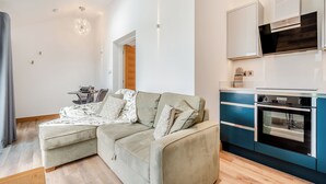 Ein modernes Wohnzimmer mit einem Ecksofa, einem Esstisch und einer Küche mit integrierten Geräten.