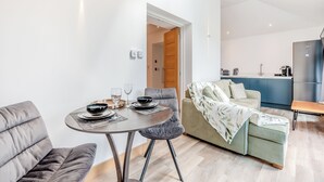 Ein moderner Wohnbereich mit Essplatz, einer Couch, einem Couchtisch und einer Küchenzeile.