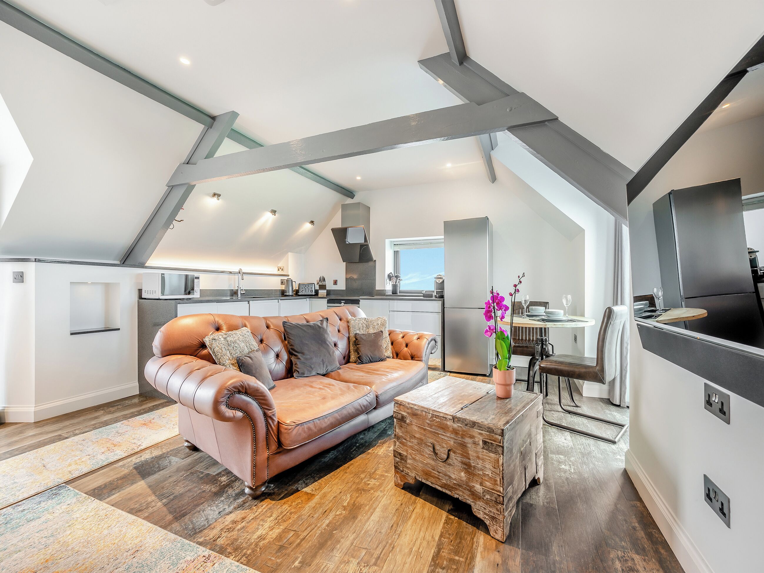 En moderne lejlighed med loft, et loftskøkken, en lædersofa og en rustik brystkasse.