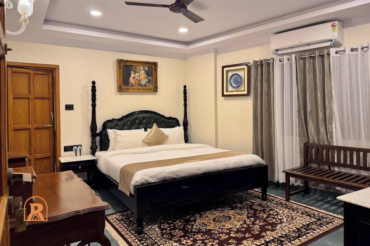 A bedroom with a bed, a ceiling fan, a nightstand, a bench, a rug, and an air conditioning unit.