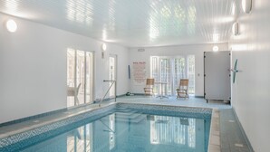 Una piscina interna con pareti di vetro trasparenti, pavimento piastrellato e un cartello con le regole scolastiche.