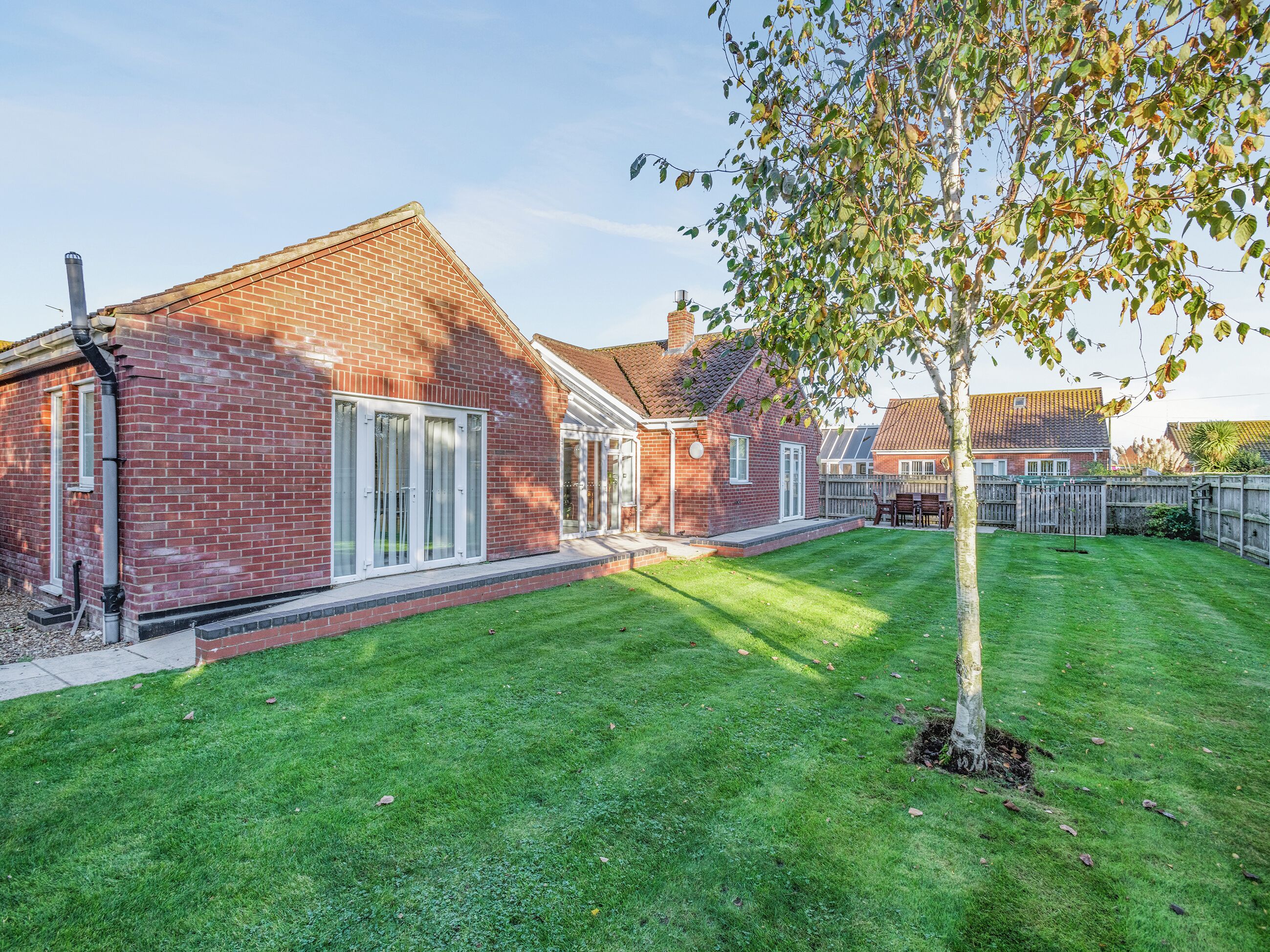 A brick house with a well-maintained lawn and a tree.