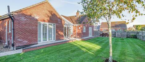 A brick house with a well-maintained lawn and a tree.