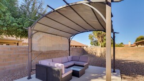 Eine Terrasse im Freien mit überdachter Sitzgruppe, einem Betonboden und einer Backsteinmauer.