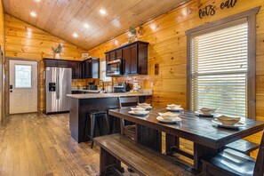 A wooden cabin kitchen with a central island, stainless steel appliances, and a dining area with benches. - Hot Tub, Games & Pool: Sevierville Family Retreat (Sevierville)