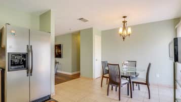 A kitchen with a refrigerator, dining table, chairs, and a chandelier.