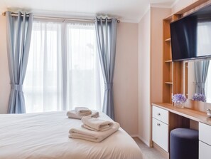 Une chambre d’hôtel équipée d’un lit, d’une télévision, d’un miroir et d’un bureau avec une chaise.