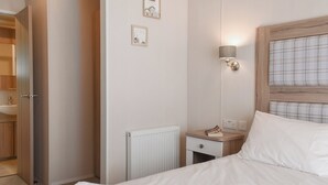 Ein Hotelzimmer mit einem Bett, einem Nachttisch mit einem Buch, einer Wandlampe und einem Heizkörper.