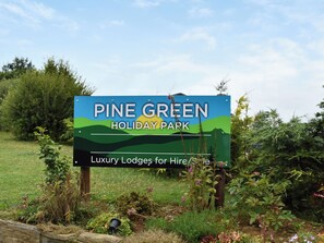 Une pancarte indiquant le parc de vacances Pine Green et faisant la publicité de chalets de luxe à la location.