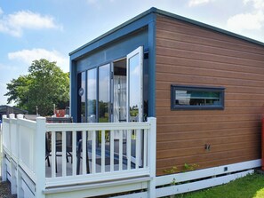 A modern mobile home with a deck, large windows, and a small attached structure. - Valley View - UK50320 (Liskeard)