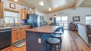 Una cocina amplia con armarios de madera, una isla central con taburetes y un comedor con vistas.