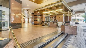 A modern lobby with a geometric ceiling design, a central escalator, and a glass entrance. - Free Parking Pool Harbor View Access Honolulu Gem! (Honolulu)
