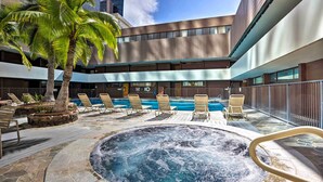 A rooftop pool area with lounge chairs, a hot tub, and palm trees. - Free Parking Pool Harbor View Access Honolulu Gem! (Honolulu)