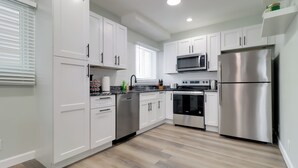 Una cocina moderna con armarios blancos, electrodomésticos de acero inoxidable y piso de madera.