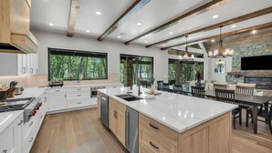 Une cuisine moderne dotée d’un grand îlot central, de meubles en bois et d’une cheminée en pierre.