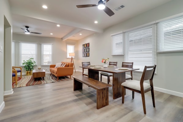 A spacious living area with a dining table, benches, and a sofa. There are ceiling fans, recessed lighting, and large windows with blinds. - Near Midtown & Medical District! Updated Unit (Detroit)
