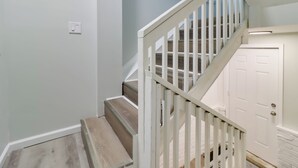 Un escalier avec des rampes blanches et des marches en bois menant à une porte blanche.