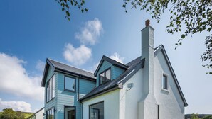A two-story house with a large patio area and a wooden table. - 4 bedroom accommodation in Blackwaterfoot (Blackwaterfoot)