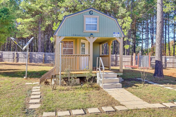 A small, single-story cabin with a porch and a 'G' on the gable.