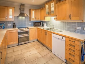 A modern kitchen with wooden cabinets, a stainless steel range hood, a microwave, a dishwasher, and a double oven. - 4 bedroom accommodation in Isle of Arran (Isle of Arran)