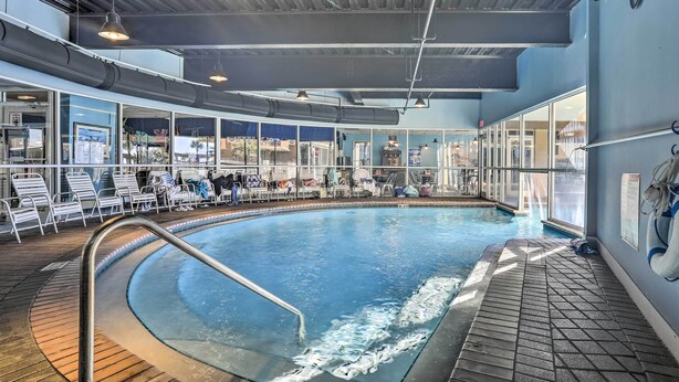 Una piscina interna con acqua cristallina, circondata da sdraio e un solarium piastrellato.