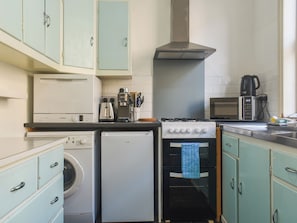 Una cocina compacta con lavadora, horno pequeño, cafetera y microondas.
