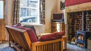 A cozy room with a wooden bench, a fireplace, a television, and a window with curtains. - 1 bedroom accommodation in Hebden Bridge (Hebden Bridge)