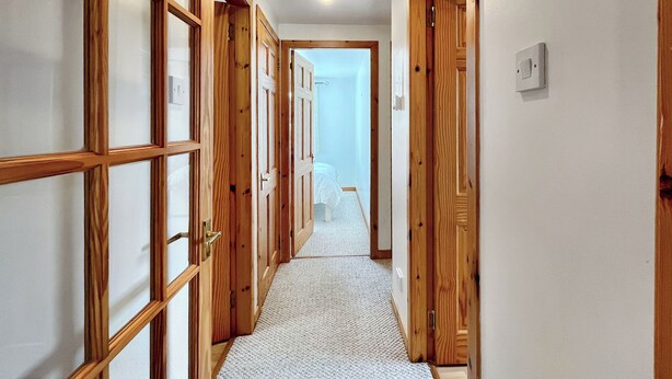 Un couloir avec des portes en bois et un sol recouvert de moquette.