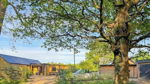 En lantlig fastighet med en grusuppfart som leder fram till en träbyggnad med ett sluttande tak.