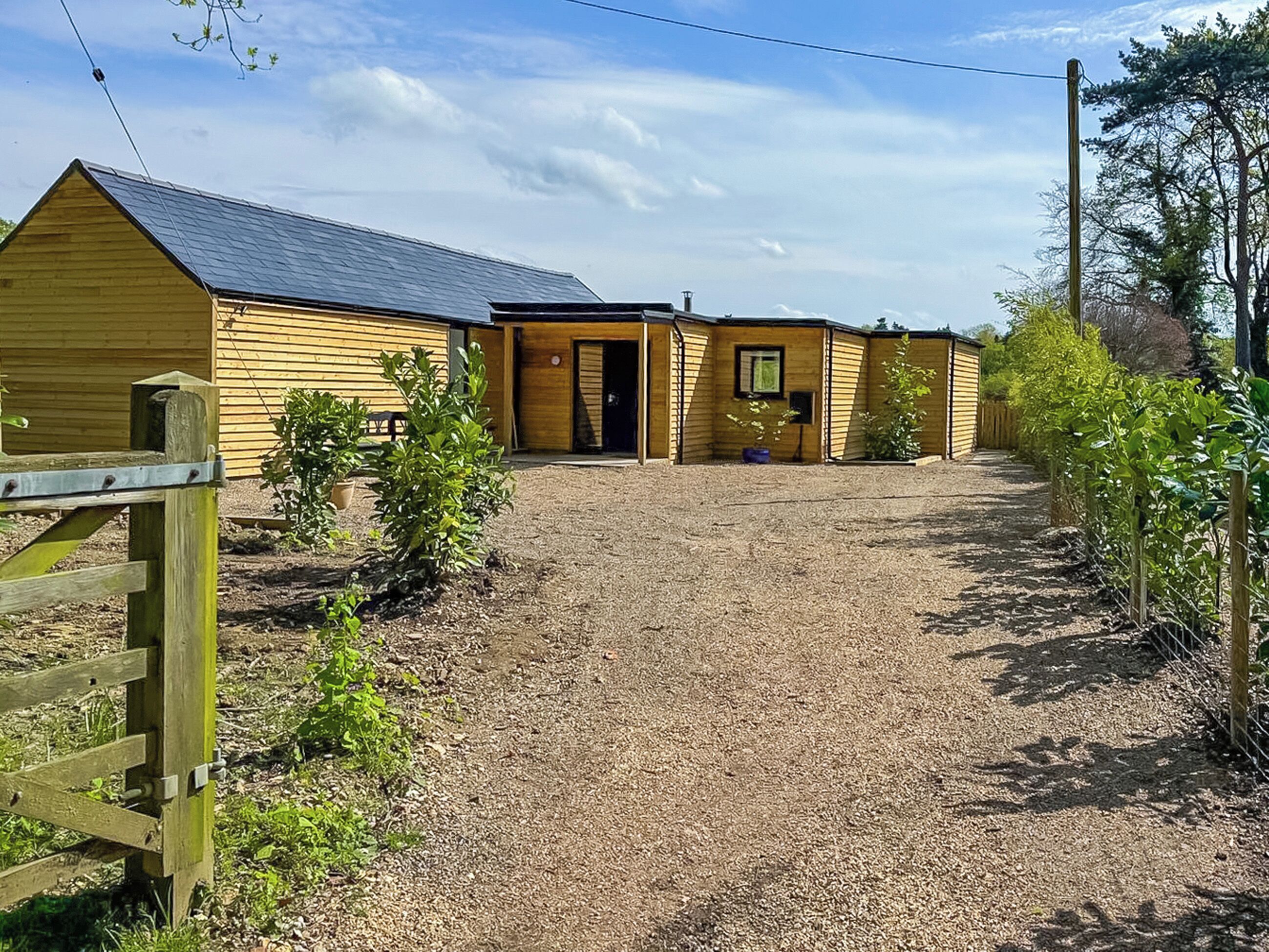 A rural property with a gravel driveway leading to a wooden building with a sloped roof.