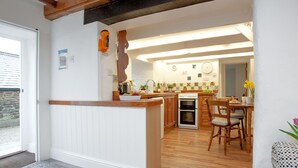 Une cuisine moderne avec des meubles en bois, un four encastré et un coin repas comprenant une table et des chaises en bois.