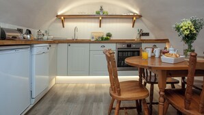 Eine Küche mit weißen Schränken, einer Holz Arbeitsplatte, einem eingebauten Backofen und einem Essbereich mit einem Holztisch und Stühlen.