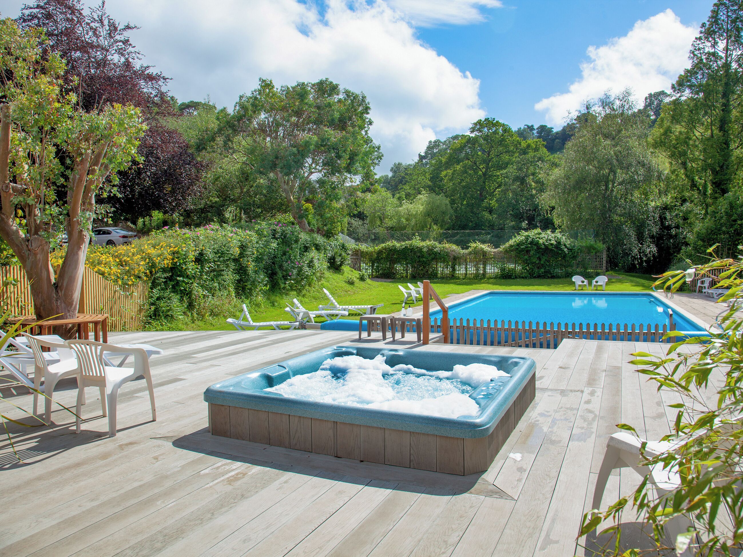 Un giardino con piscina, vasca idromassaggio e lettini.