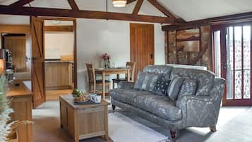 A cozy living room with a grey patterned sofa, wooden coffee table, and a dining area with a wooden table and chairs.