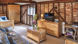 Un salon chaleureux avec un canapé, une table basse en bois et un téléviseur posé sur un meuble en bois.
