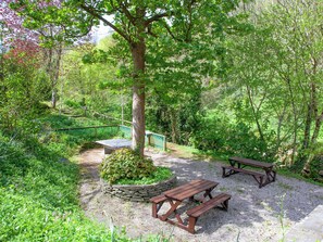 Ein Picknickplatz mit zwei hölzernen Bänken und einem Steinpflanzgefäß mit Grünpflanzen.