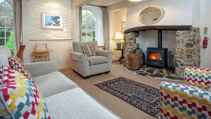 A cozy living room with a fireplace, comfortable seating, and large windows. - Tuckenhay, Clock Tower Cottage - FJG (Bow Creek, between Dartmouth and Totnes)