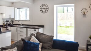 Un salon moderne comprenant un canapé, un coin repas, une cuisine avec un lave-linge et une grande fenêtre.