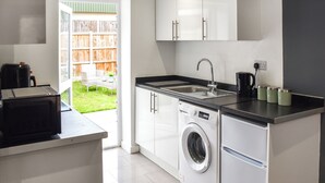 A compact kitchen with a washing machine, a sink, and a coffee maker. - Sunflower Bungalow - UK50569 (Little Dunham, near Kings Lynn)