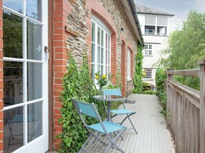 A brick building with a sign reading 'Mill Spring.' There are two blue chairs and a small table outside. - Tuckenhay, Mill Spring - FMF (Bow Creek, between Dartmouth and Totnes)