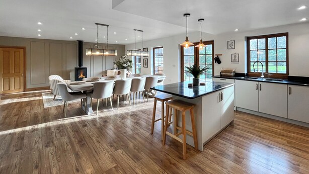 A modern kitchen with a central island, wooden flooring, and pendant lighting. - 5 bedroom accommodation in St. Asaph (St. Asaph)
